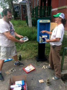 Dutchtown Volunteers Benjamin Thomas and Terri Zeman prepare the old pay phone stand for conversion to a free little library.