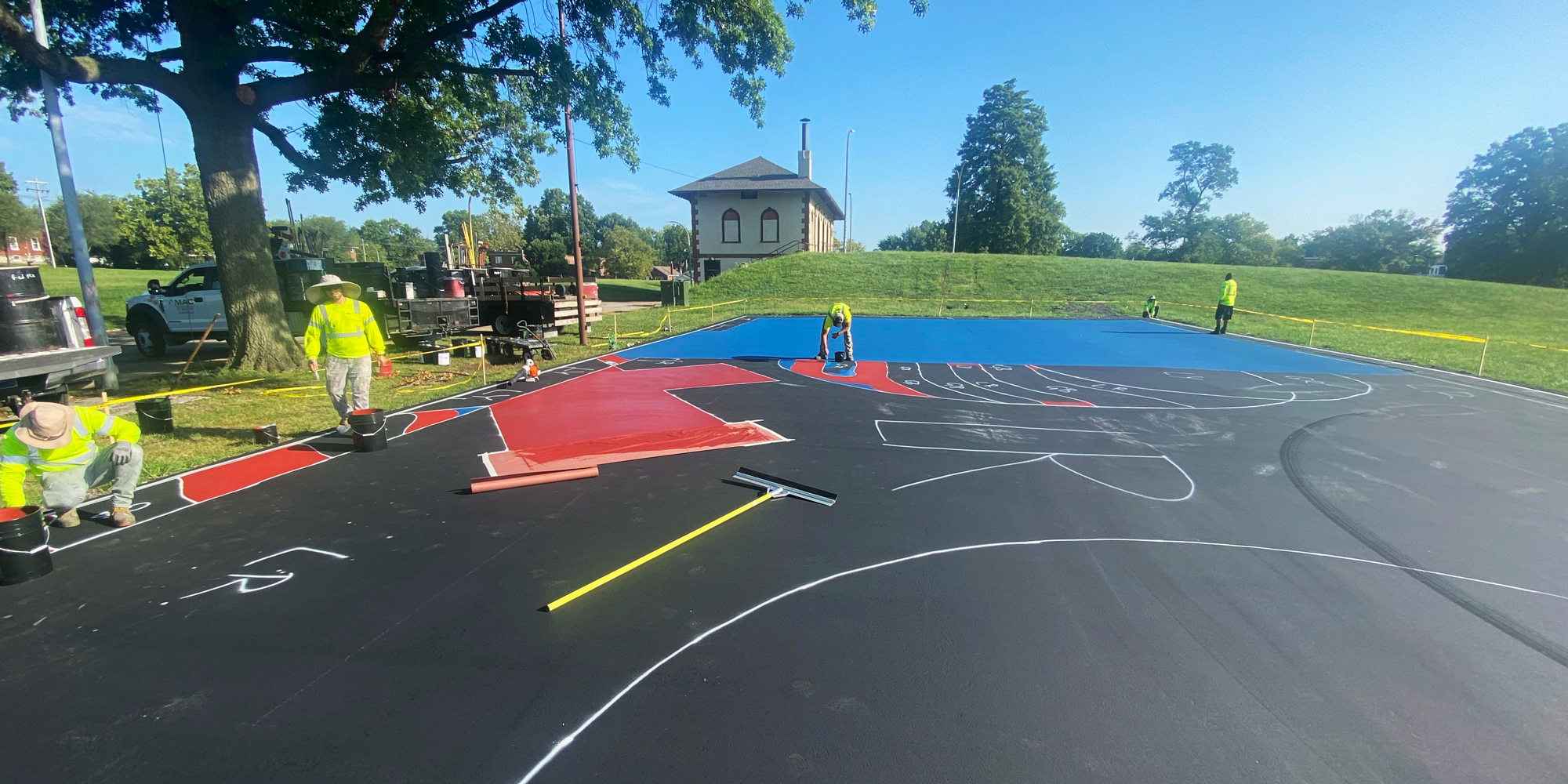 Workers painting the mural on the futsal court at Marquette Park.